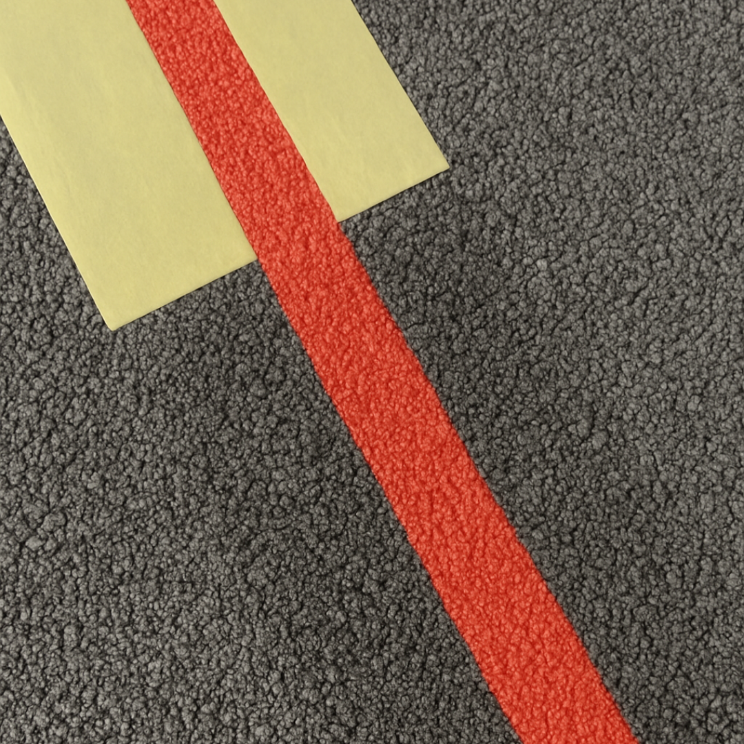 Trait de peinture de traçage rouge appliqué sur sol asphalté.