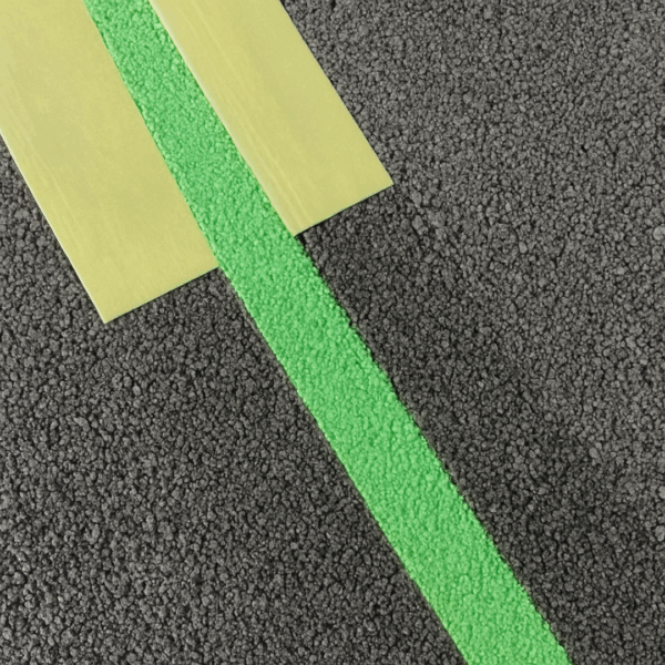 Ligne verte réalisée avec une peinture de traçage verte sur enrobé, avec ruban de masquage.