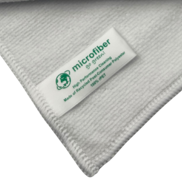 Gros plan sur l'étiquette d'un chiffon du lot de 20 microfibres recyclées. L'étiquette indique 'microfiber go green', '100% rPET' et 'Made of Recycled Post-Consumer Polyester'. On distingue nettement la texture douce et absorbante du tissage blanc